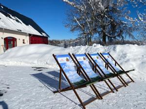 una señal en la nieve junto a un granero rojo en Zur Bergwiese 5 Sterne Appartementhaus, en Fürstenau