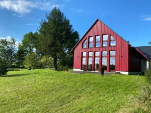 eine rote Scheune mit großen Fenstern auf einem grünen Feld in der Unterkunft Zur Bergwiese 5 Sterne Appartementhaus in Fürstenau