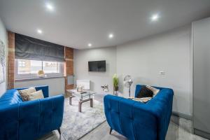 a living room with two blue couches and a table at Hotl Aparts at Merchants House in Bradford