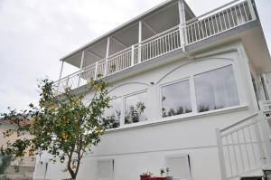 a white house with a balcony on top of it at Rose rooms at island of Rab in Rab