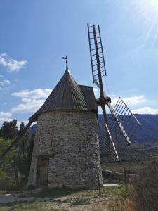 a windmill on a hill with the sun in the background at Chambre d'hôtes les trois chemins in Cucugnan