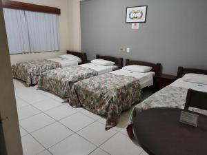 a group of four beds in a room with a table at Hotel Parador Indaial in Indaial