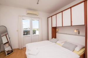 a bedroom with a large white bed and a window at Apartments and Rooms Mare in Vodice