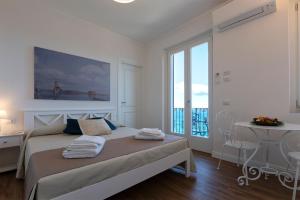 Un dormitorio blanco con una cama y un balcón. en Terrazza & Romantica sospese sul mare del Borgo Antico --- Terrace & Romantic over the sea of the Ancient Village, en Castelsardo
