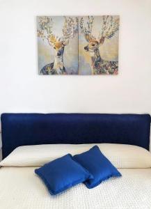 zwei Gemälde von Hirschen an der Wand über einem Bett in der Unterkunft Dependance Rosetta in Minori