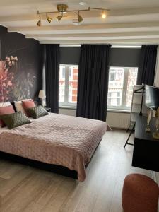 een slaapkamer met een bed, een tv en ramen bij BnB Bruxelles in Venlo