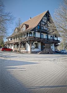 un grand bâtiment en bois avec une voiture garée devant. dans l'établissement Kräuterhex' Reutin, à Alpirsbach