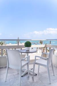 stół i krzesła na balkonie z widokiem na ocean w obiekcie Kalamaki Mare Suites w mieście Kalamaki