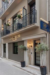 ein Gebäude mit zwei Topfpflanzen davor in der Unterkunft Classic Hotel by Athens Prime Hotels in Athen
