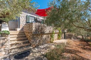 a house with a stone wall with a red umbrella at House Jure in Tkon