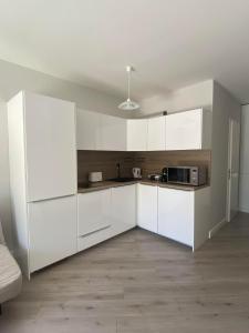 Biała kuchnia z białymi szafkami i kuchenką mikrofalową w obiekcie Aida Apartman Siófok w Siófoku