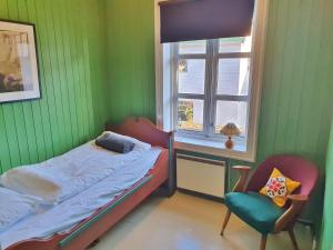 um quarto com uma cama, uma cadeira e uma janela em Heimbrygga Restaurant & Accommodation em Skrova