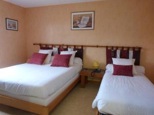 two beds in a hotel room with white and red pillows at Logis hôtel Les Confins du perche in Sceaux-sur-Huisne