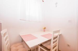 une table blanche et des chaises dans une pièce avec une fenêtre dans l'établissement Apartments and Room Zinka, à Vodice 19 autres photos