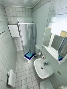 biała łazienka z prysznicem i umywalką w obiekcie Abschalten im Zentrum von Bad Ischl w mieście Bad Ischl
