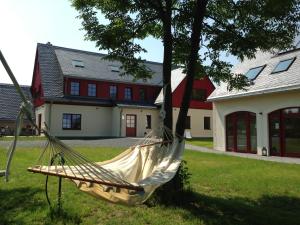 a hammock hanging from a tree in front of a house at Zur Bergwiese 5 Sterne Appartementhaus in Fürstenau