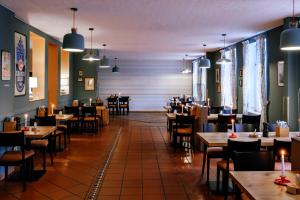a dining room with tables and chairs and lights at SCHULZENS Brauerei & Hotel in Tangermünde
