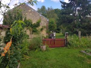 a dog standing behind a red fence in a garden at Le Clos de la Canardière in Savigny-sur-Braye