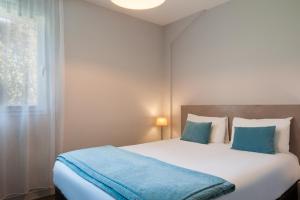 a bedroom with a large white bed with blue pillows at The Originals Boutique, Hôtel La Grange, Niort (Qualys-Hotel) in Niort