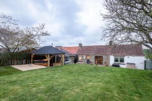 an exterior view of a house with a large yard at East Cottage * Wood Burning Hot Tub * Garden in St. Andrews