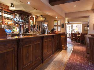 a bar in a pub with wooden cabinets at Wheatsheaf, Baslow by Marston's Inns in Baslow