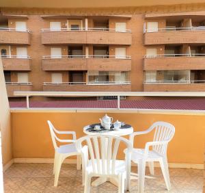 einen Tisch und Stühle auf einem Balkon mit einem Gebäude in der Unterkunft ACV - Isla Park-1ª Linea Planta 1 Sur in Oropesa del Mar
