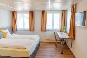 a bedroom with two beds and a desk with a table at Gasthaus Engel Hasle in Hasle