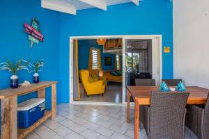 uma sala de jantar com paredes azuis e uma mesa e cadeiras em Studio at the pool in tropical Resort Seru Coral with privacy and large pool em Willemstad