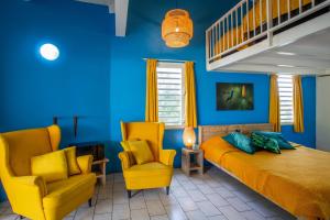 a blue room with a bed and two chairs at Studio at the pool in tropical Resort Seru Coral with privacy and large pool in Willemstad +22 photos