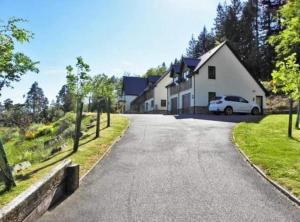 a house with a car parked on the side of a road at An Outdoor Enthusiasts Piece of Heaven in Gairlochy