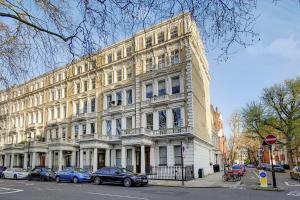 a large white building with cars parked in front of it at The Kensington Gardens Collection- by Short Stories London in London
