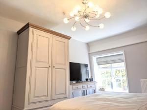 a bedroom with a large white cabinet and a television at The Bell Inn in Thorpe le Soken