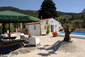 eine Terrasse mit Stühlen, einem Sonnenschirm und einem Pool in der Unterkunft Quinta da Granja Gardener's cottage in Coimbra