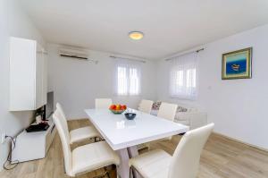 a white dining room with a white table and chairs at House Ivana in Vinišće