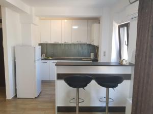 a kitchen with two bar stools and a refrigerator at Aparthomes Fundeni in Bucharest