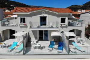 ein Haus mit einer Terrasse mit Stühlen und Sonnenschirmen in der Unterkunft Sunrise Bay Apts in Ayia Evfimia