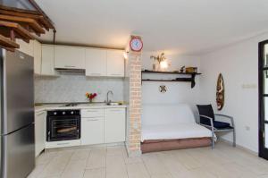 a kitchen with white cabinets and a table and a clock at House Renato in Ivan Dolac