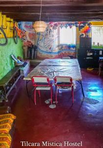 stół i 2 krzesła w pokoju z graffiti w obiekcie Tilcara Mistica Hostel w mieście Tilcara