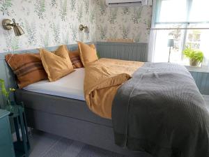 a bed with brown pillows on it in a bedroom at B&B Bland ormbunkar och rosor in Falkenberg