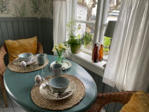 una mesa con platos y cuencos delante de una ventana en B&B Bland ormbunkar och rosor en Falkenberg