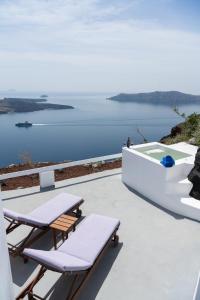 eine Terrasse mit 2 Liegestühlen und einer Badewanne in der Unterkunft Iatis View Collection in Imerovigli