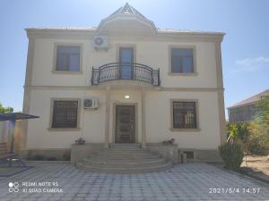 uma grande casa branca com uma escada em frente em Cozy House in Bina, Bolluq em Baku