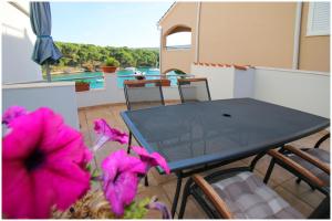 einen Tisch und Stühle auf einem Balkon mit rosa Blumen in der Unterkunft Apartments Elvis in Primošten
