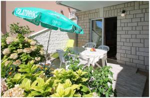 einen Tisch, Stühle und einen Regenschirm auf einer Terrasse in der Unterkunft Apartments Elvis in Primošten