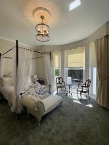 a bedroom with a bed and chairs and a chandelier at Glenorleigh in Torquay