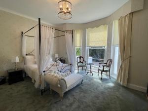 1 dormitorio con cama con dosel, mesa y sillas en Glenorleigh, en Torquay
