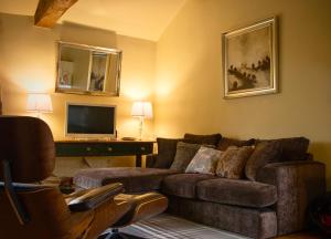 a living room with a couch and a television at Priesthill HotTub Pool Dog Friendly PeakDistrict in Stanton in Peak