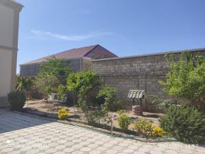 a brick wall with a garden in front of a house at Cozy House in Bina, Bolluq in Baku