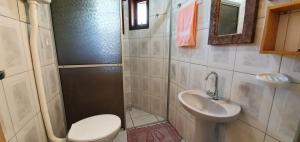 a small bathroom with a toilet and a sink at Pousada Charle Brown in Garopaba
