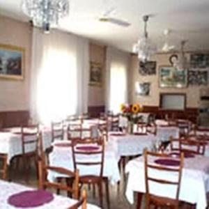 a dining room with white tables and wooden chairs at HOTEL ROSSINI in Rimini +21 photos